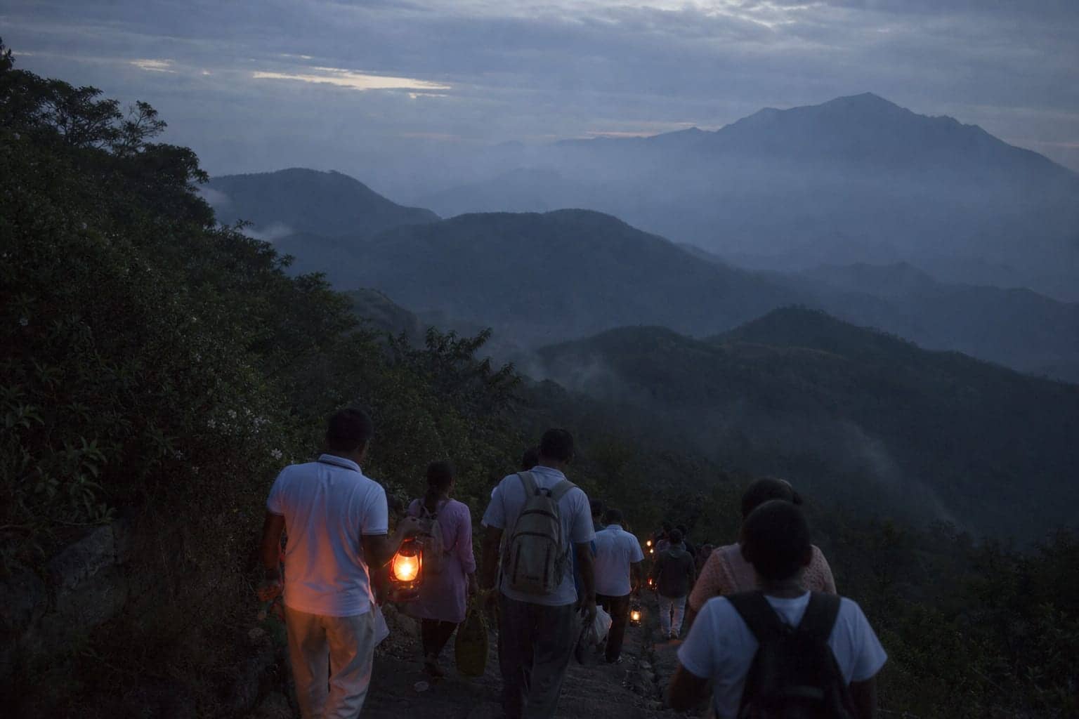 Lamps and pilgrims on a mountain path in Sri Lanka before dawn