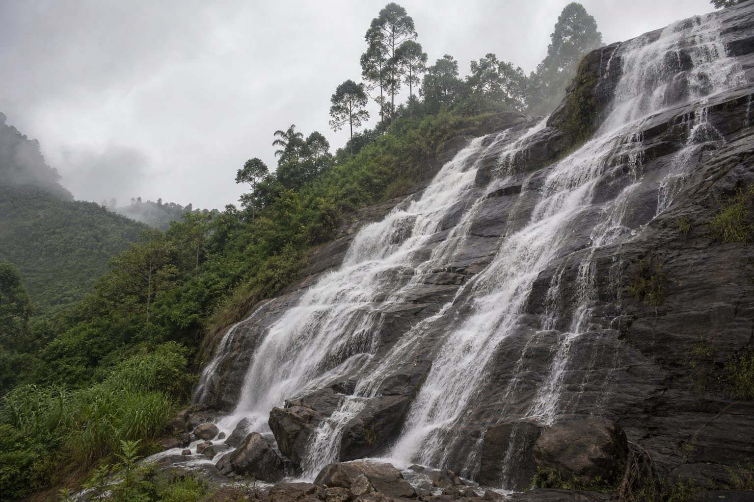 Water falling in wide cascades over dark rock beside the Wellawaya road near Ella