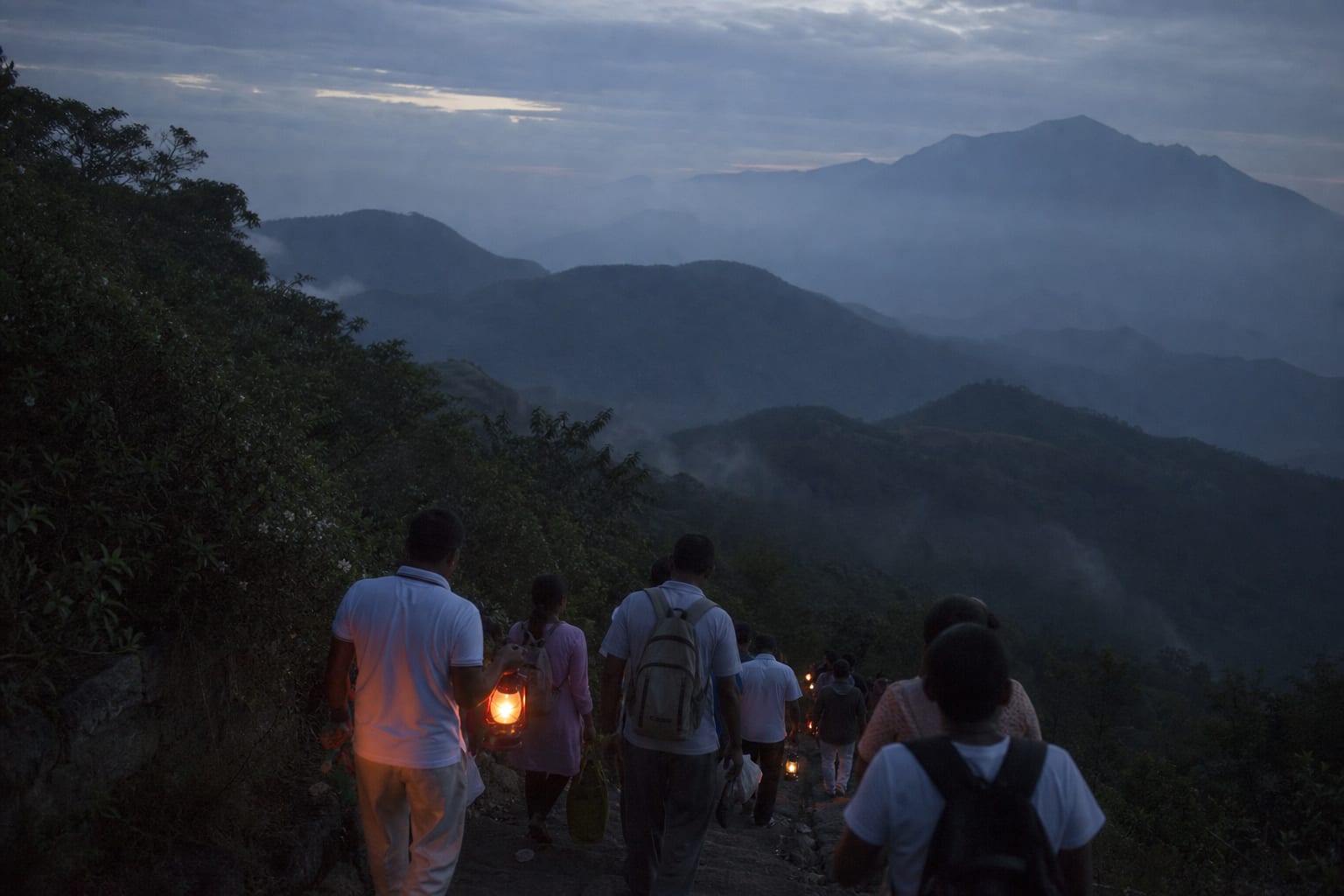 Lamps and pilgrims on a mountain path in Sri Lanka before dawn