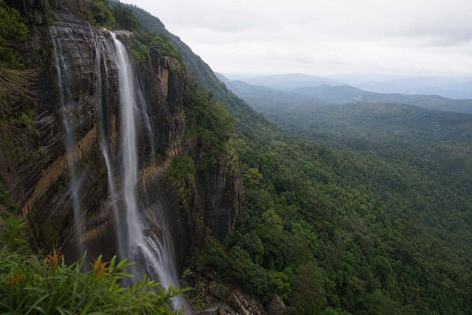 Water dropping over a high rock face into forest below in Sri Lanka's Uva province